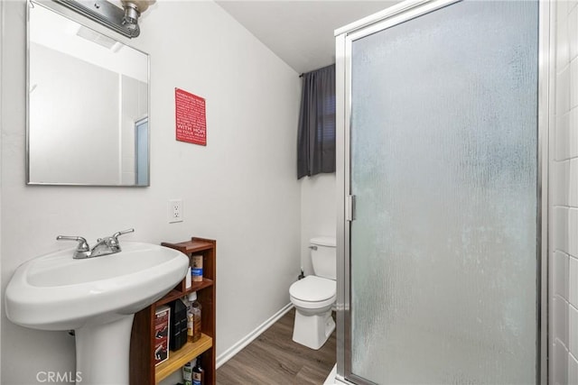 bathroom with toilet, a shower with door, and hardwood / wood-style flooring