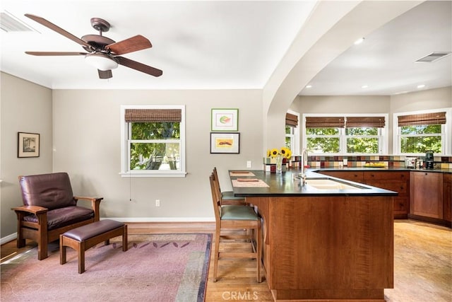 kitchen with a kitchen breakfast bar, ceiling fan, and sink