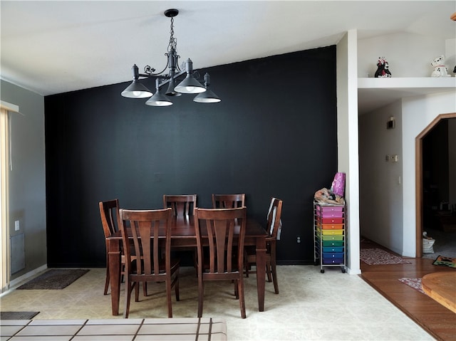 dining area featuring light wood-type flooring, a chandelier, and vaulted ceiling