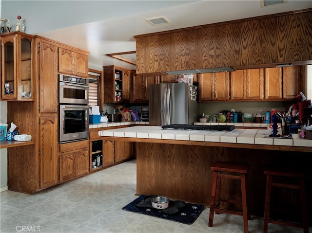 kitchen featuring appliances with stainless steel finishes, tile counters, and kitchen peninsula