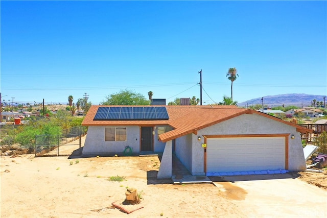 view of front facade featuring a mountain view, solar panels, and a garage