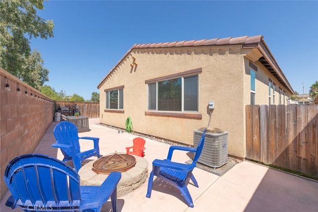 rear view of house with a fire pit, a patio, and central AC