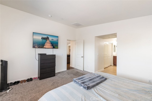 bedroom with connected bathroom and light colored carpet