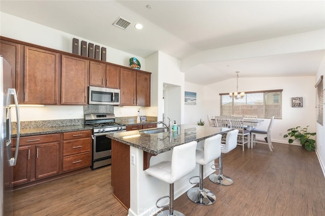 kitchen featuring sink, stainless steel appliances, dark hardwood / wood-style floors, vaulted ceiling, and a center island with sink