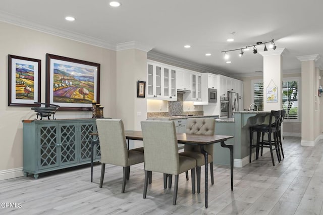 dining space with ornamental molding and light hardwood / wood-style floors