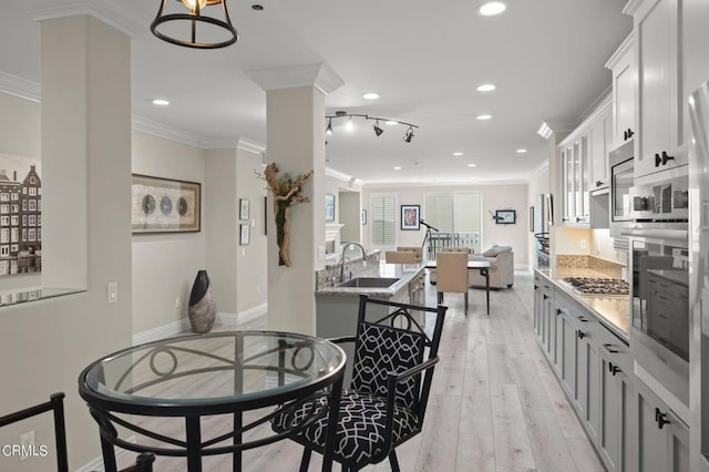 dining space featuring ornamental molding, sink, and light hardwood / wood-style floors