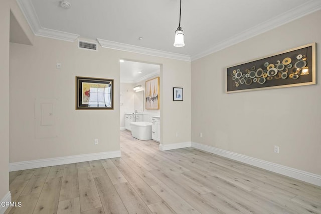 empty room featuring ornamental molding and light wood-type flooring