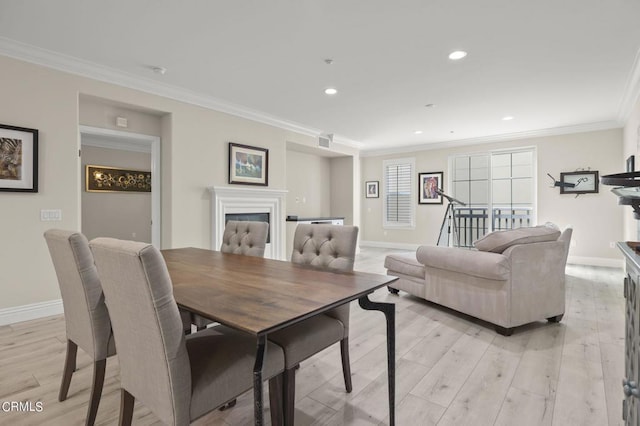 dining space with light wood-type flooring and crown molding