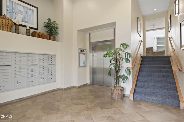 foyer entrance featuring a high ceiling, mail boxes, and elevator