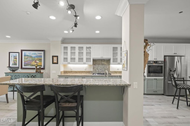 kitchen with a breakfast bar area, appliances with stainless steel finishes, light hardwood / wood-style flooring, and white cabinetry