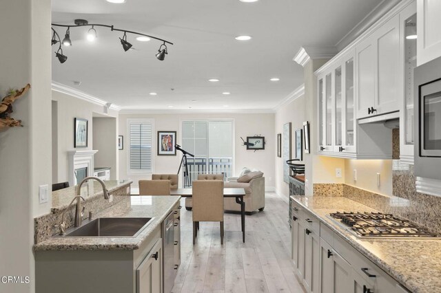 kitchen with light wood-type flooring, white cabinets, sink, crown molding, and appliances with stainless steel finishes