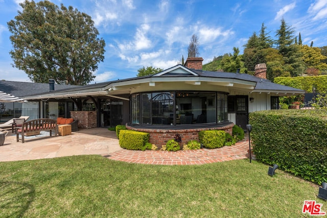 rear view of property featuring a patio area, an outdoor living space, and a yard