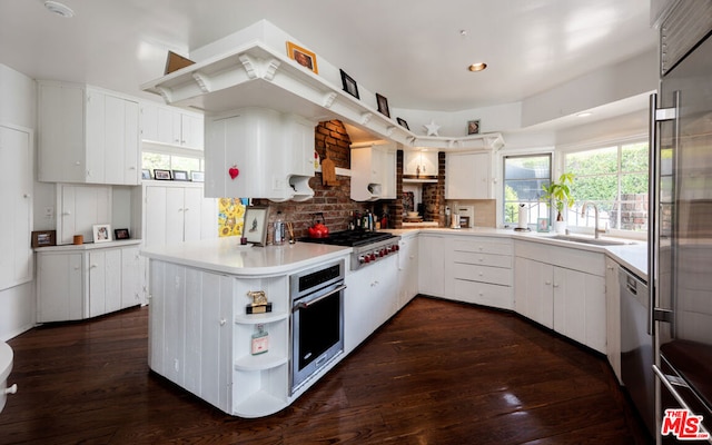 kitchen with appliances with stainless steel finishes, white cabinetry, dark wood-type flooring, and sink