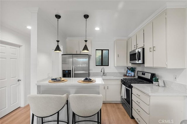 kitchen with white cabinetry, sink, hanging light fixtures, stainless steel appliances, and light wood-type flooring