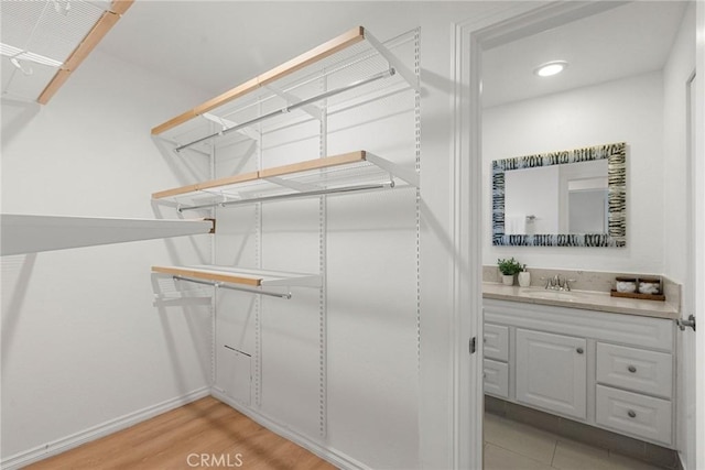 spacious closet with light hardwood / wood-style floors and sink