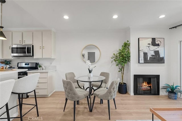 dining space featuring light wood-type flooring and ornamental molding