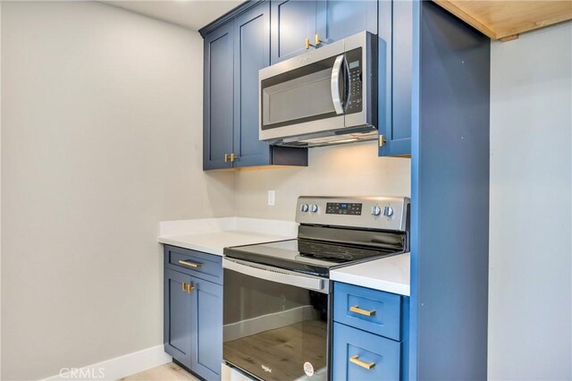 kitchen with appliances with stainless steel finishes, light hardwood / wood-style floors, and blue cabinetry