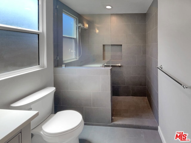 bathroom with tile patterned floors, toilet, vanity, and tiled shower