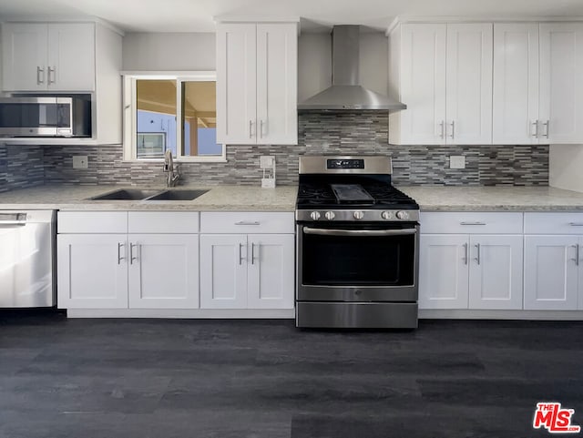 kitchen featuring backsplash, white cabinets, sink, wall chimney exhaust hood, and appliances with stainless steel finishes