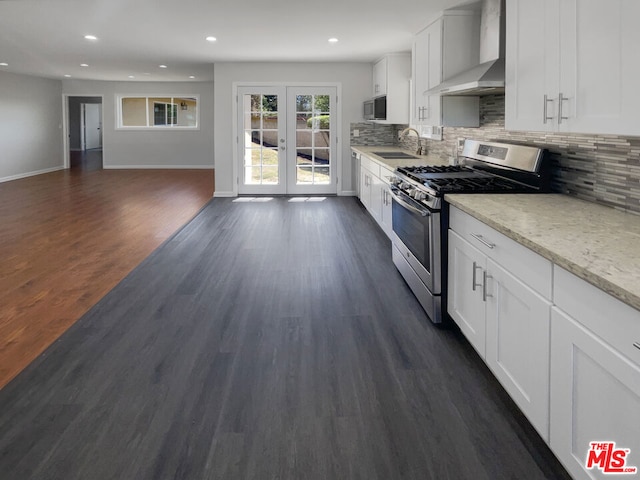 kitchen featuring french doors, stainless steel appliances, wall chimney range hood, dark hardwood / wood-style flooring, and white cabinets