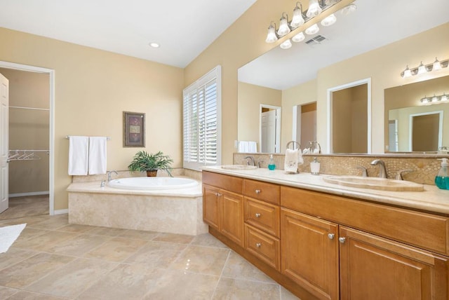 bathroom with vanity, a relaxing tiled tub, tile patterned flooring, and tasteful backsplash