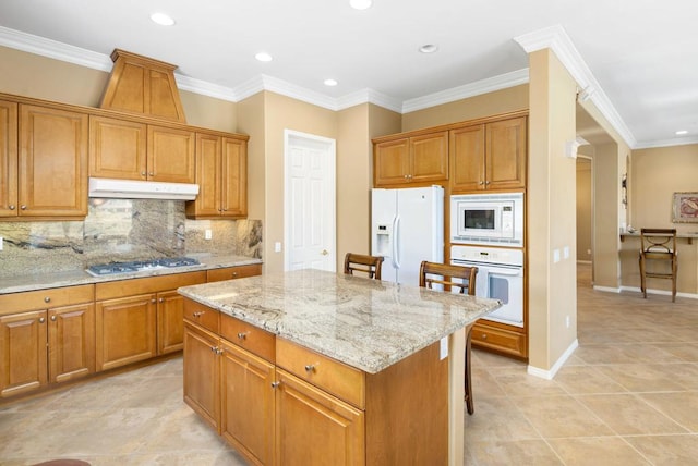 kitchen featuring a breakfast bar, backsplash, white appliances, a kitchen island, and ornamental molding