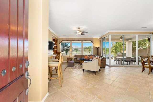 tiled living room with ceiling fan and crown molding