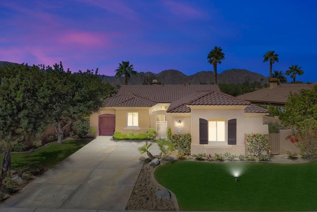 mediterranean / spanish house with a mountain view, a garage, and a yard