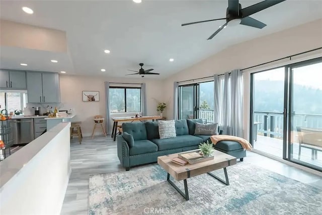 living room with ceiling fan, a healthy amount of sunlight, light wood-type flooring, and vaulted ceiling