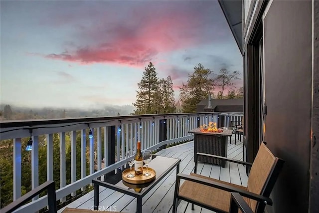 balcony at dusk featuring an outdoor fire pit