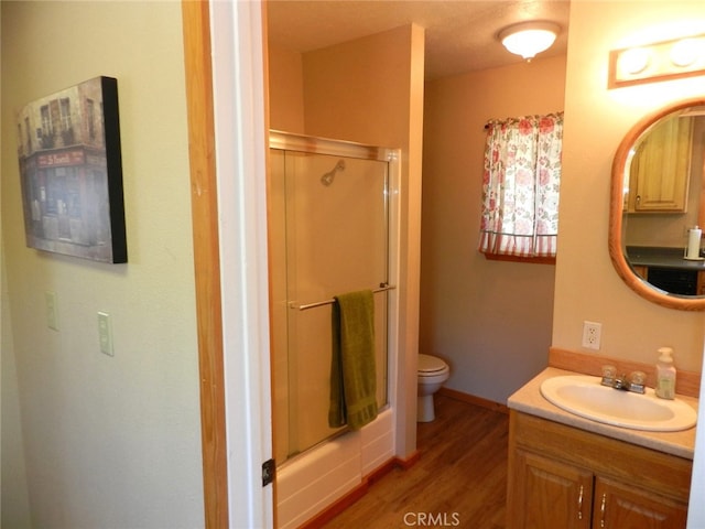 bathroom featuring toilet, an enclosed shower, hardwood / wood-style flooring, and vanity