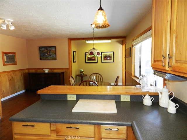 kitchen with a textured ceiling, decorative light fixtures, and dark hardwood / wood-style flooring