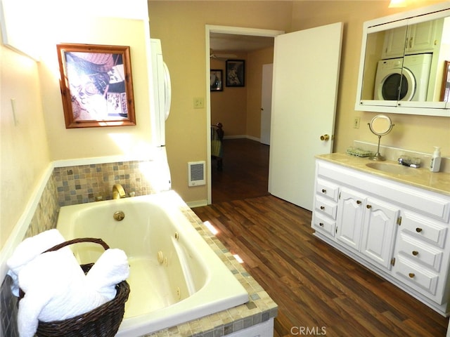 bathroom with vanity, a bathing tub, hardwood / wood-style floors, and washer / clothes dryer