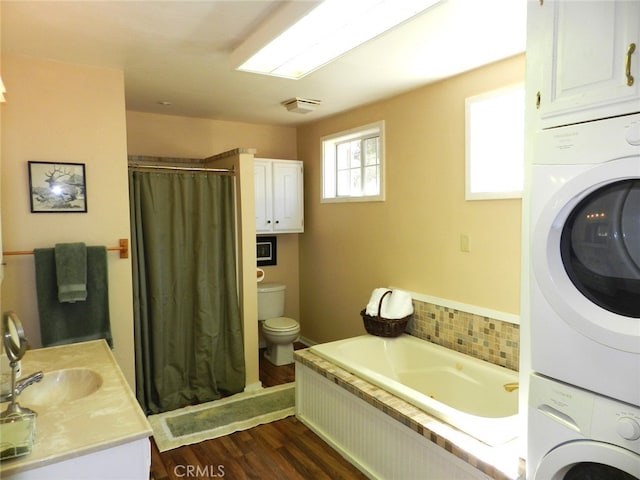 full bathroom with toilet, independent shower and bath, wood-type flooring, sink, and stacked washer / dryer