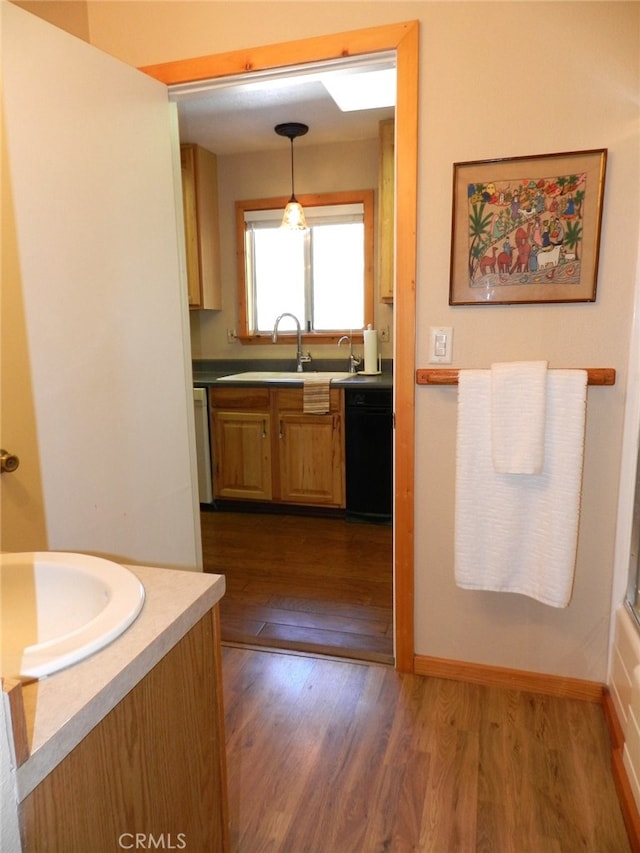 kitchen featuring dark wood-type flooring, sink, decorative light fixtures, and dishwasher