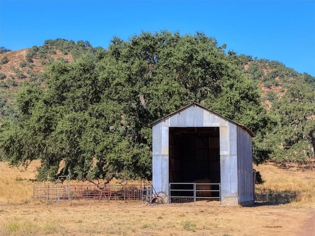 view of outbuilding featuring an outbuilding, a wooded view, and fence
