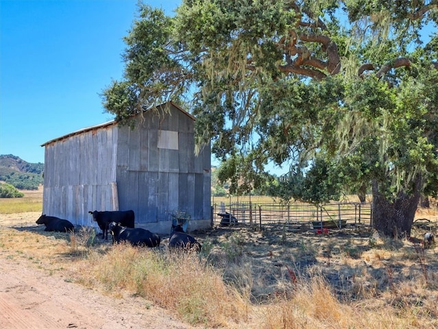 view of outbuilding featuring an outbuilding, a rural view, and fence