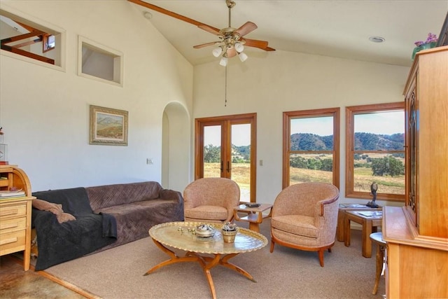 living room with arched walkways, a mountain view, high vaulted ceiling, a ceiling fan, and french doors