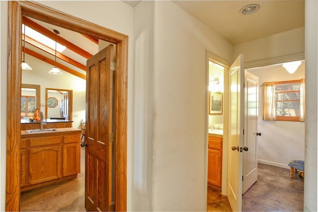 corridor featuring vaulted ceiling with beams, baseboards, and a sink