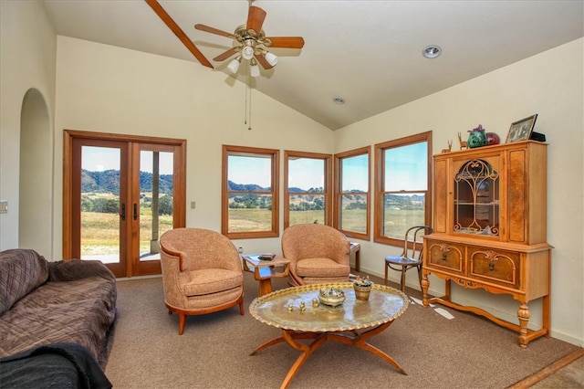 living area with arched walkways, lofted ceiling, a mountain view, carpet flooring, and french doors