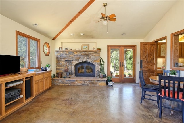 living room with finished concrete flooring, a ceiling fan, french doors, a stone fireplace, and high vaulted ceiling