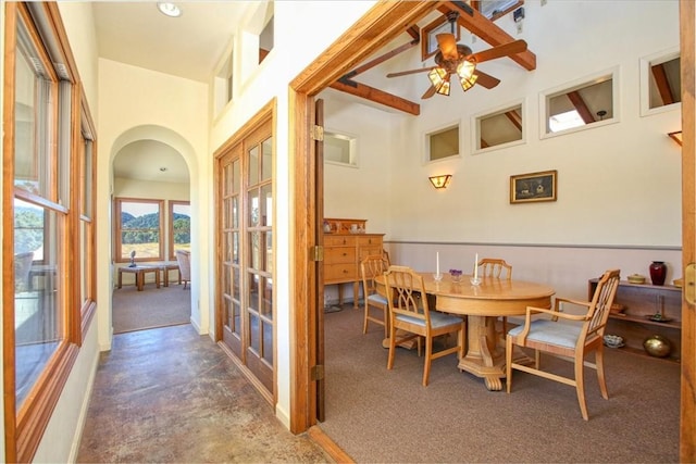 dining area with a ceiling fan, arched walkways, french doors, and a towering ceiling