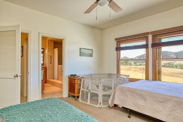 bedroom with ceiling fan, ensuite bath, and light colored carpet