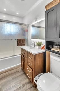 full bathroom featuring toilet, enclosed tub / shower combo, vanity, and wood-type flooring