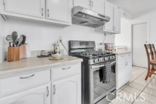 kitchen with gas stove, white cabinets, and light tile patterned floors