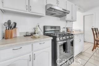 234 E Raymond St, Compton, CA 90220 - kitchen with stainless steel gas range oven, under cabinet range hood, light countertops, light tile patterned flooring, and white cabinetry