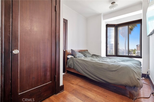 bedroom with light wood-type flooring and crown molding