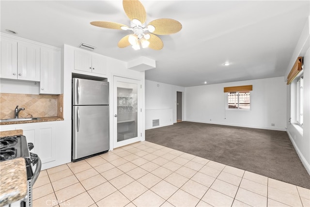 kitchen with ceiling fan, white cabinetry, stainless steel refrigerator, black range with gas stovetop, and sink