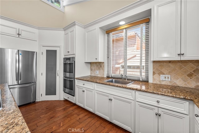 kitchen featuring appliances with stainless steel finishes, dark hardwood / wood-style floors, white cabinetry, and dark stone counters