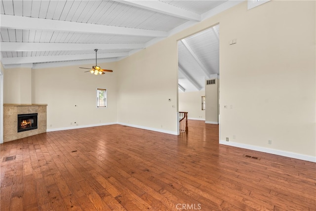 unfurnished living room featuring hardwood / wood-style flooring, lofted ceiling with beams, ceiling fan, and a tiled fireplace